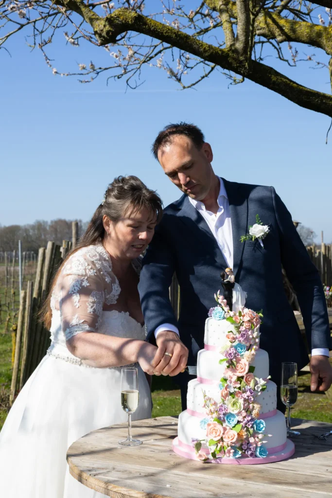 Het bruidspaar snijd samen de bruidstaart aan.