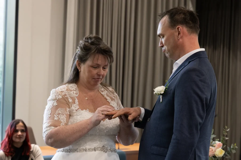 De bruid schuift de trouwring om de vinger van de bruidegom tijdens de ceremonie.