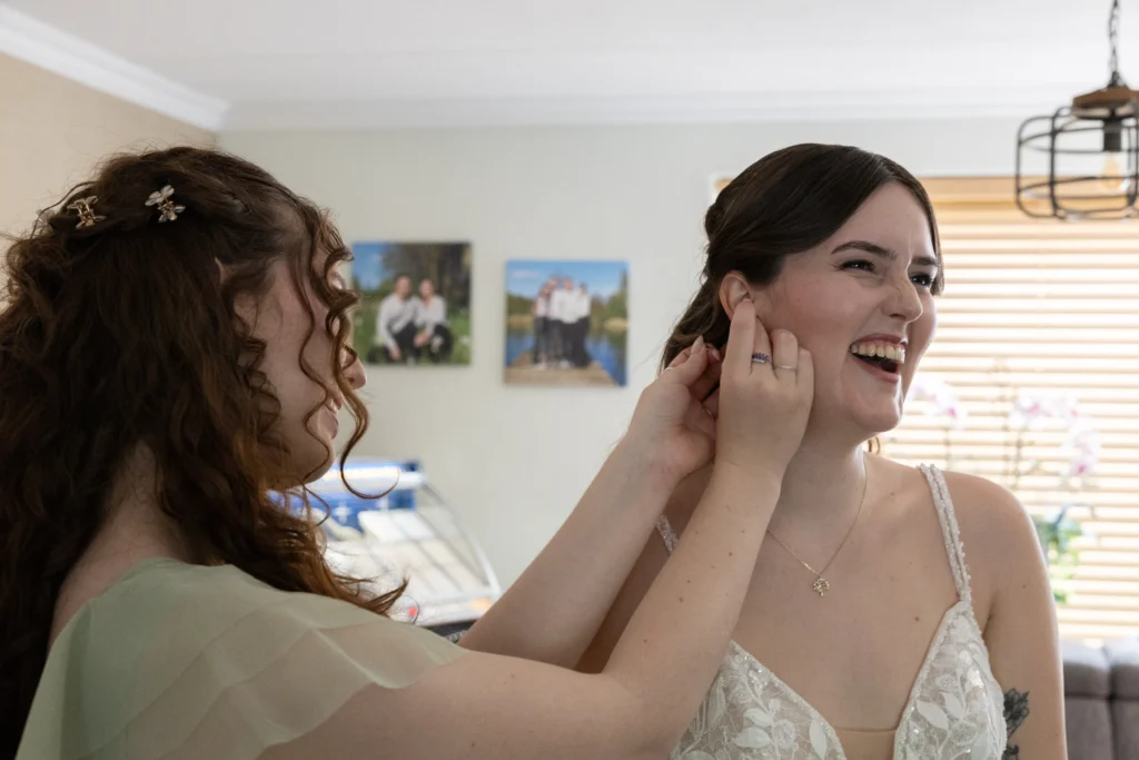 Spontane lach tussen vriendinnen bij het opmaken van de bruid gefotografeerd door Romy van Forever and more